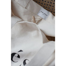 Load image into Gallery viewer, detail of top inside part of natural organic bag, poésie privée logo sewn above wooden toggle closure
